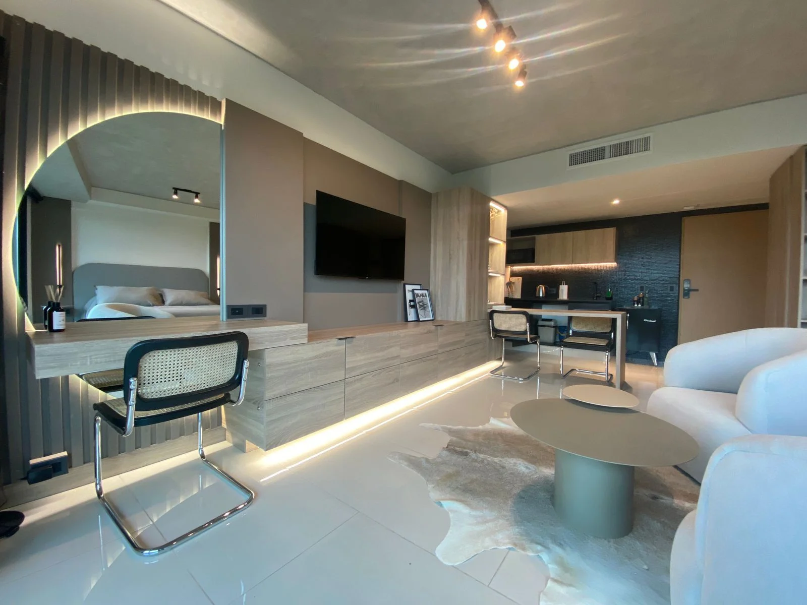 Luxury interior with illuminated mirror, desk and kitchen area